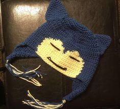 a crocheted hat with a smiling cat on it's face and eyes