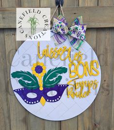 a mardi gras sign hanging on the side of a wooden fence with a bow