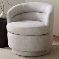 a white chair sitting on top of a rug next to a vase