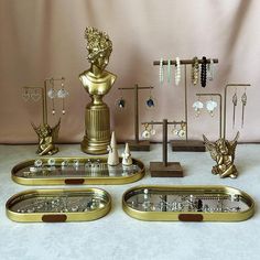 there are three trays with jewelry on them and one has a statue in the middle