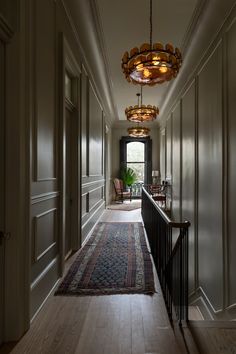 the hallway is lined with wooden paneling and chandelier hanging from the ceiling