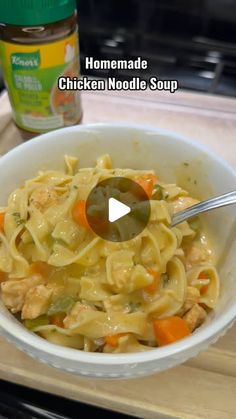 a bowl filled with chicken noodle soup on top of a wooden cutting board next to a jar of mayonnaise