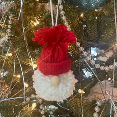 a santa hat ornament hanging from a christmas tree