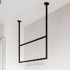 an empty room with three coat hooks hanging from the ceiling