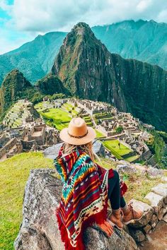 a woman sitting on top of a rock next to a mountain