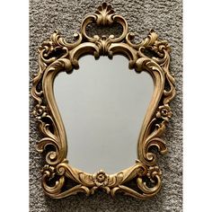 an ornate gold framed mirror is on the wall next to a carpeted flooring