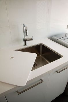 a white sink sitting under a window next to a counter top with a metal faucet