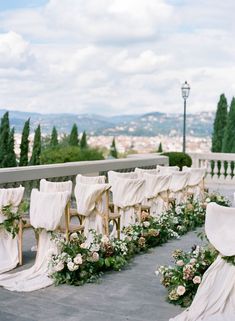 the chairs are covered with white cloths and flowers for an outdoor wedding ceremony in italy