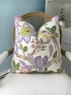 a white chair with a floral pillow on it's back and a blue wall in the background