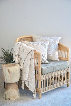 a wicker chair with pillows and a blanket on it next to a tree stump