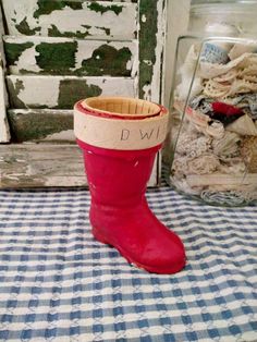 a red boot sitting on top of a table next to a jar filled with dirt