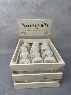 a wooden box filled with bottles of alcohol sitting on top of a gray floor next to a sign that says recovery kits