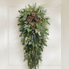 a wreath hanging on the wall with pine cones and greenery