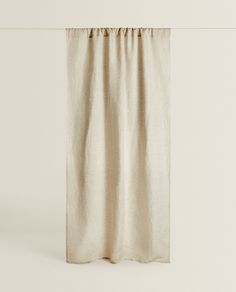 a curtain hanging on a white wall with no curtains in front of it and an object next to the curtain