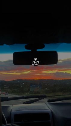 the sun is setting in the distance as seen from inside a car's dashboard