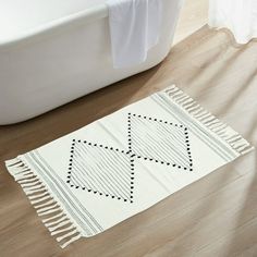 a bath tub sitting next to a white rug on top of a wooden floor in a bathroom