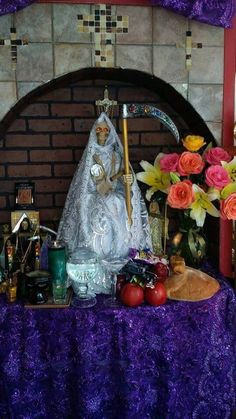 a statue of the virgin mary in front of flowers and other items on a table