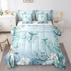 an ocean themed comforter set on a bed in a room with white walls and furniture