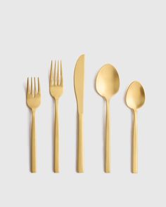 gold flatware is laid out on a white surface