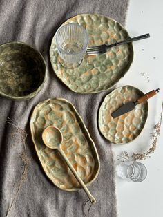 three bowls and two spoons sitting on top of a table cloth next to each other