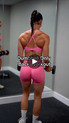 a woman in pink shorts and white socks is holding a dumbbell while looking at her reflection