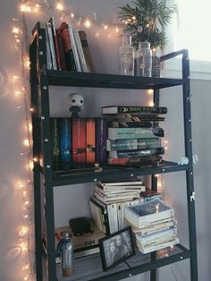 a bookshelf filled with lots of books next to a window covered in fairy lights