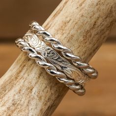 two silver rings sitting on top of a piece of wood