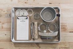 an assortment of kitchen utensils in a metal tray on a wooden table top