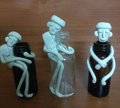 three bottles with figures sitting in them on a table