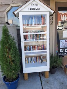 there is a white book case with books on it in front of the library building