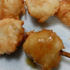 four fried food items sitting on top of a piece of paper with toothpicks sticking out of it