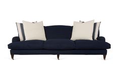 a blue couch with three pillows on top of it and two white pillows on the back