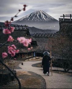 a woman walking down a path with an umbrella in front of a snow covered mountain