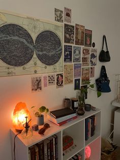 a book shelf with many books on top of it next to a wall covered in posters