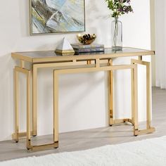 a console table with glass top and metal legs in a white living room, next to a painting on the wall