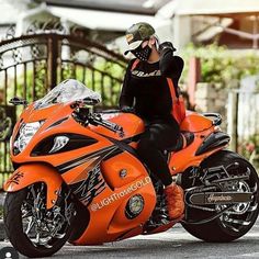 a woman sitting on top of an orange motorcycle