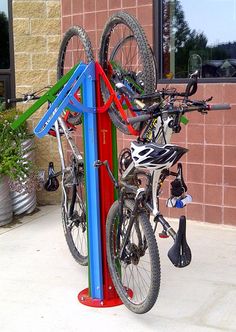 there are two bikes that are on the bike rack in front of this building and one is blue, green, red, and white