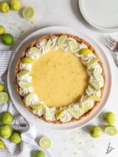 a lemon pie on a white plate with limes around it