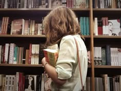 a woman standing in front of a bookshelf with many shelves full of books