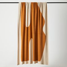 an orange and white curtain hanging on a black rod with the curtains pulled back to reveal it's shape