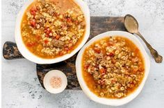 two bowls filled with soup sitting on top of a cutting board