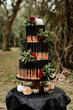 a three tiered cake sitting on top of a table covered in leaves and flowers