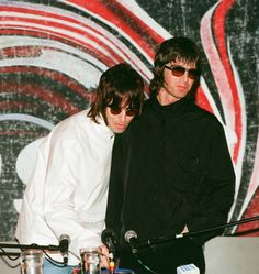 two young men standing next to each other in front of microphones on a stage