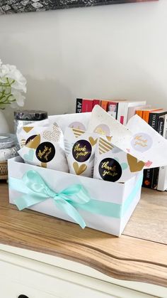 a white box filled with chocolates sitting on top of a wooden table next to a vase