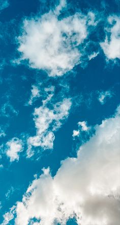 the airplane is flying high in the blue sky with white clouds above it and below