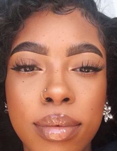 a close up of a woman with makeup on her face and nose piercings in front of her mouth