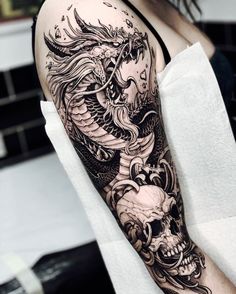 a woman's leg with a dragon and skull tattoo on the side of her thigh