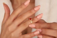 a woman's hand holding an engagement ring with a red stone on the middle