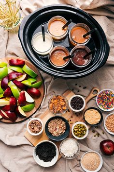 apples, cereals and other foods are arranged in bowls on top of a table