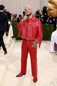 the singer is dressed in red leather and has his hand on his mouth as he sings